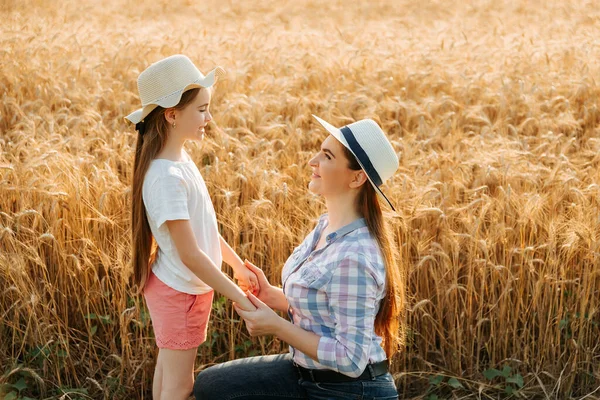 Söt kaukasisk bonde familj med hatt liten flicka och hennes mamma håller hand och talar i vetefält. — Stockfoto