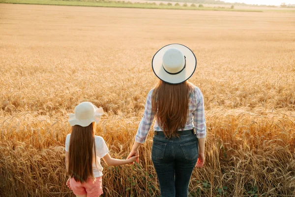 Vista posterior, mujer e hija niño con sombrero en la cabeza examina tierras de cultivo, —  Fotos de Stock