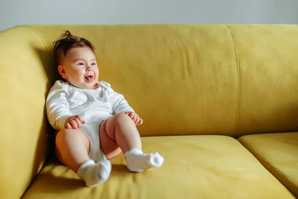 Bambino è seduto sul divano giallo a casa. — Foto Stock