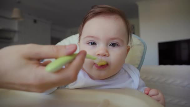 Amerikaanse moeder voeden een baby met een lepel, in de woonkamer achtergrond — Stockvideo