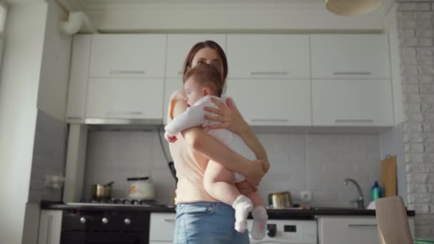 Madre abrazo bebé en casa en la cocina. — Vídeo de stock