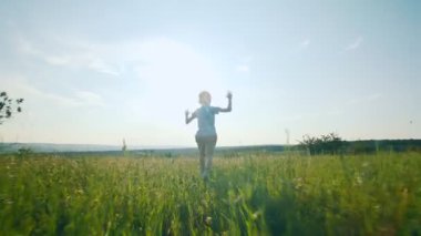 Genç bir çocuk bir tarlada kollarını açarak koşunun ortasında yakalandı. Bu görüntü özgürlüğü, saf duyguyu ve çocuk olmanın eğlenceli özünü yansıtıyor..