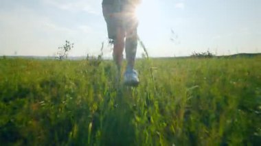 Yüzü öne dönük çocuk doğada koşarken sevinçten kollarını kaldırarak yükseğe sıçrıyor. Görüntü ham çocukluk enerjisini, eğlenceyi ve doğal özgürlüğü yakalar..