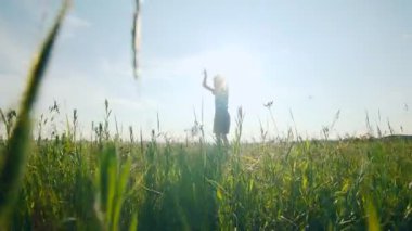 Neşeli bir çocuk çimenli bir arazide kollarını kaldırarak ve gülümseyerek yükseğe zıplar. Bu an doğanın kalbindeki saf mutluluk, hareket ve özgürlüğü yakalar..