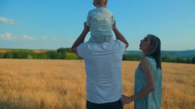 Bir aile, güneşli bir arazide yürümekten zevk alır. Bebeklerini taşırken el ele tutuşurlar. Barışçıl manzara onların bağlanma zamanlarını arttırır..