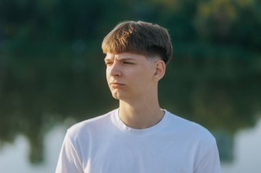 Sakin ve doğal bir ortamda, genç bir çocuk doğrudan bakışlarıyla ciddi bir ifade sergiler. Yumuşak güneş ışığı ve Bokeh arka planı iç gözlemci ve barışçıl bir atmosfer yaratır..