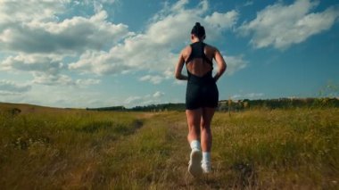 Arkadan, yokuş yukarı koşan sportif bir kızı takip ediyoruz. Sıkı çalışıyor, hızlı hareket ediyor, nefesinin ritminde, patikada ve yaz sıcağında kayboluyor..