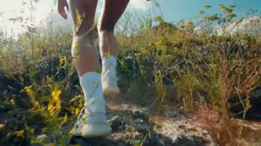 Genç ve zinde bir kadın güneşli bir günde kayalık bir patikada koşarken arkadan görülüyor. Yoğun açık hava egzersizi, dayanıklılık, adanmışlık ve doğa ve zindelik sevgisini gösteriyor..