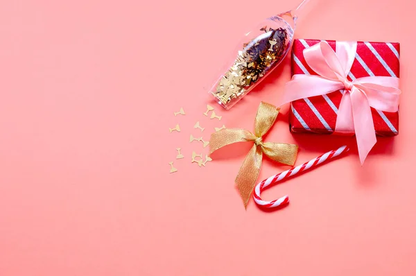 Kerstcompositie met geschenkdozen, kerstmuts, champagneglas en decoraties op roze achtergrond — Stockfoto
