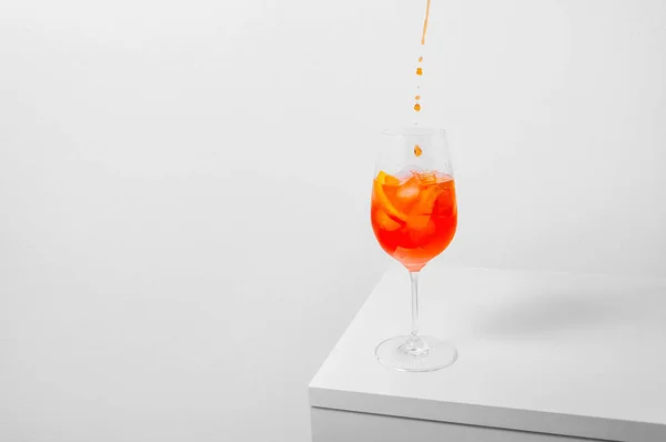 Cocktail Aperol Spritz. Verser l'aperol dans un verre à vin avec de la glace sur fond blanc. Concept créatif minimal — Photo