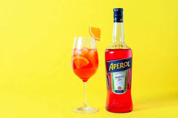 Lugansk, Ukraine - 29 mars 2021 : Aperol Spritz Cocktail. Aperol en bouteille et verre à vin avec glace sur fond jaune — Photo