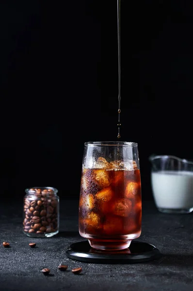 IJskoffie gieten in groot glas op donkere achtergrond. Concept Verfrissend zomerdrankje — Stockfoto