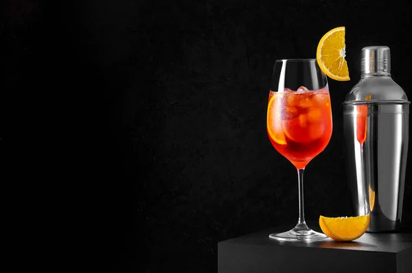 Aperol Spritz Cocktail dans un verre à vin avec shaker et tranche d'orange sur fond sombre. Longue boisson gazeuse — Photo