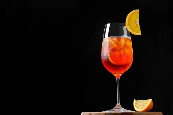 Aperol Spritz Cocktail em copo de vinho com gelo e fatia de laranja sobre fundo escuro. Bebida longa e gasosa. — Fotografia de Stock