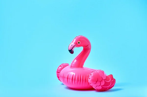 Inflatable pink flamingo pool toy on blue background. Creative minimal concept.