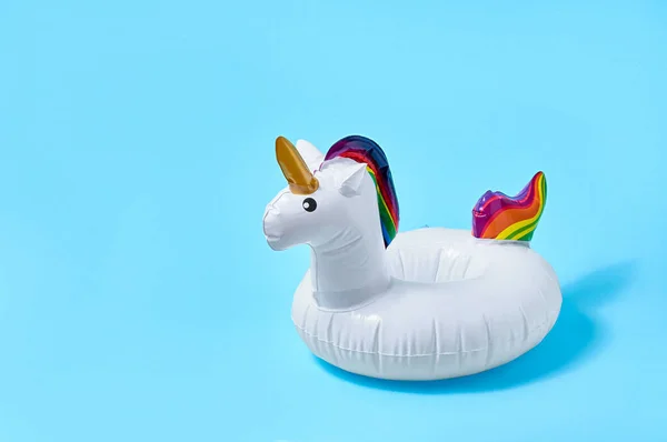 Inflatable white unicorn pool toy on blue background. Creative minimal concept.