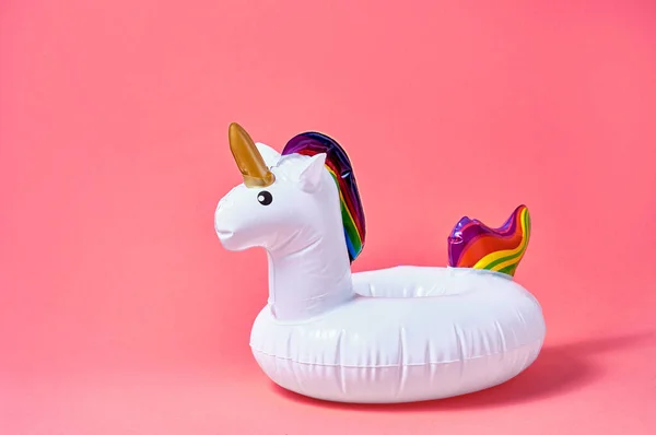 Inflatable white unicorn pool toy on pink background. Creative minimal concept.