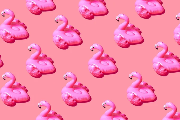 Inflatable pink flamingo pool toy pattern on pink background. Creative minimal summer concept.
