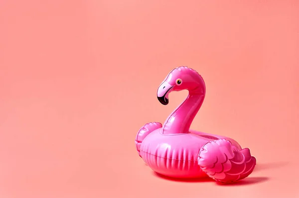 Inflatable pink flamingo pool toy on pink background. Creative minimal concept.