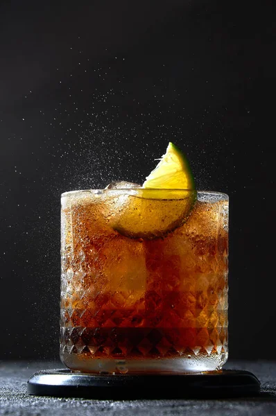 Cuba Libre of Long Island Cocktail met rum, cola en limoen in glas. Natriumspray op donkere achtergrond. Verfrissend zomerdrankje — Stockfoto