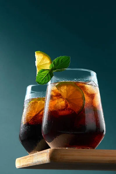 쿠바 리브레 (Cuba Libre) 또는 롱 아일랜드 칵테일 (Long Island Cocktail), 럼, 콜라, 라임을 어두운 청색 배경에 있는 나무보드에 안경을 쓴 것이다. 상쾌 한 여름 음료 — 스톡 사진