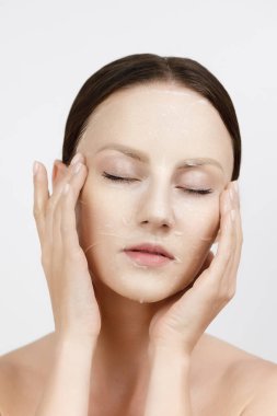 Yüz bakımı Kore kozmetik ürünlerini nemlendiriyor. Sağlıklı Taze Cilt Üzerine Beyaz Maske Uygulayan Güzel Kadın Portresi. Yüz derisindeki kumaş maskesi. Yüksek Çözünürlük