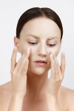 Yüz bakımı Kore kozmetik ürünlerini nemlendiriyor. Sağlıklı Taze Cilt Üzerine Beyaz Maske Uygulayan Güzel Kadın Portresi. Yüz derisindeki kumaş maskesi. Yüksek Çözünürlük