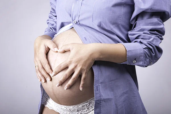 Zwangere vrouw die haar handen op baby bump Rechtenvrije Stockfoto's