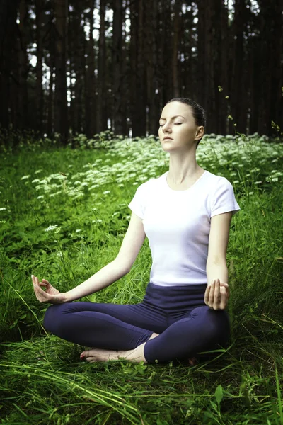 Chica joven practicando yoga en un bosque — Foto de Stock