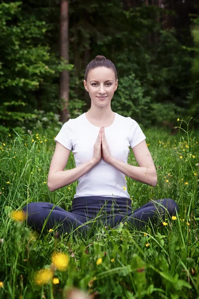 Chica joven practicando yoga en un bosque — Foto de Stock