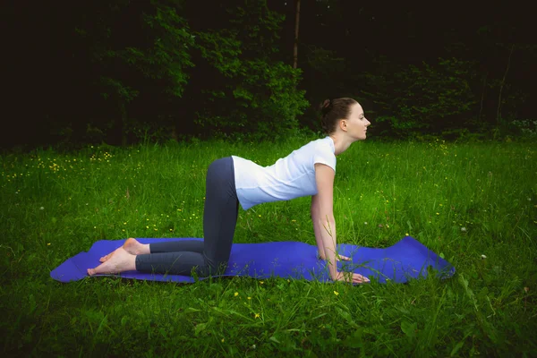 Beautiful woman working out yoga excercises mardzhariasana on fitness mat — Stock Photo, Image