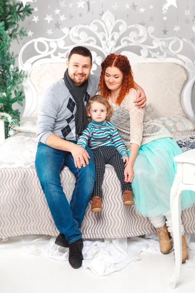 Retrato de la familia madre padre hijo sentado en la cama en estilo navideño — Foto de Stock