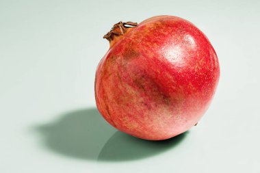 Taze olgun nar meyvesi, soluk yeşil bir zemin üzerinde yansıması ile