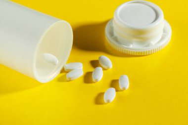 İlaçlar, sarı arka planda beyaz haplar..