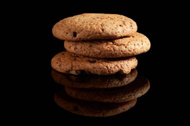 Parlak siyah arka planda üç çikolatalı kurabiye.