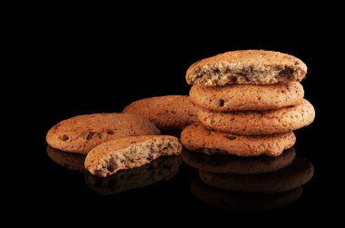 Parlak siyah arka planda çikolata parçacıklı kurabiyeler.