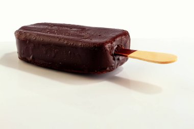 Çubukta dondurma, çikolata kremalı, arka planda yoğunlaşma damlacıkları.