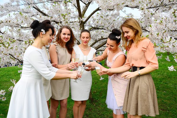 Девушки с шампанским празднуют в саду Сакуры
.