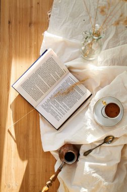 Tahta bir masada kahve fincanı. Bir kitapla güneşli bir sabah.