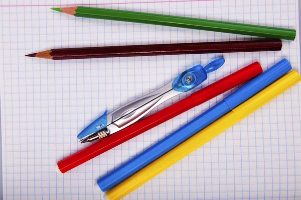 Pencils, pen, compass on exercise book page — Stock Photo, Image