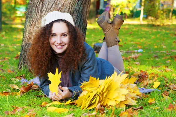 Krásná elegantní žena ležící v parku na podzim — Stock fotografie