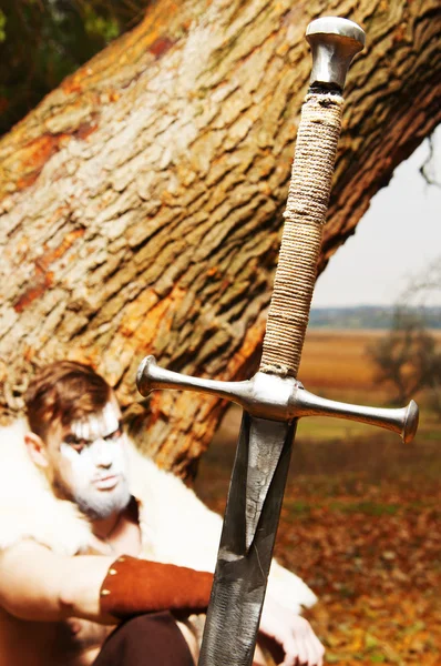 Portret van een gespierde oude krijger. Zwaard in de voorgrond — Stockfoto