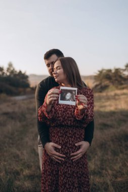 Bebek ultrason fotoğrafı olan mutlu genç çift.