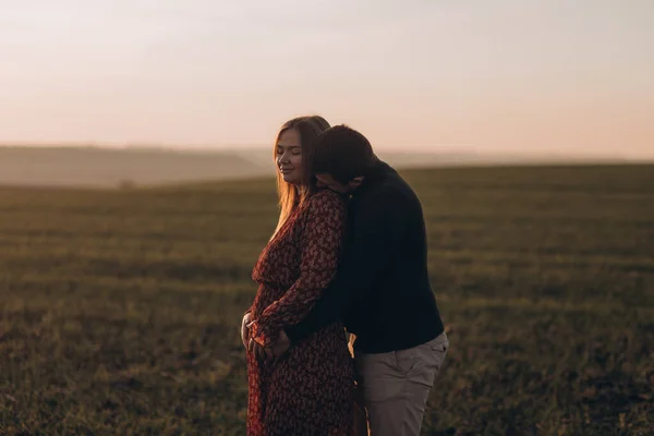 丈夫和怀孕的妻子一边接吻一边享受户外时光 — 图库照片