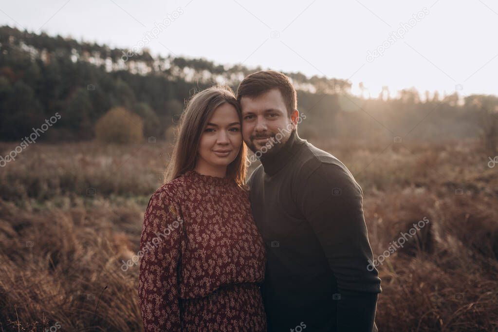 Beautiful young pregnant pregnant happy couple walking in the autumn field
