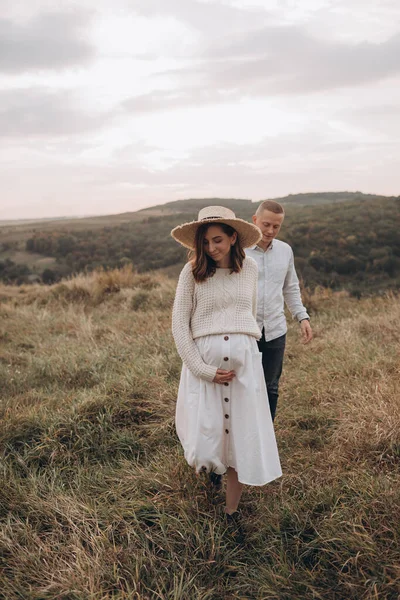 幸せな若い妊娠中のカップルが山を歩く — ストック写真