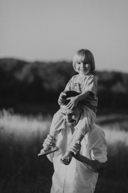 Küçük çocuk yazın gün batımında tarlada babasıyla oynuyor. 