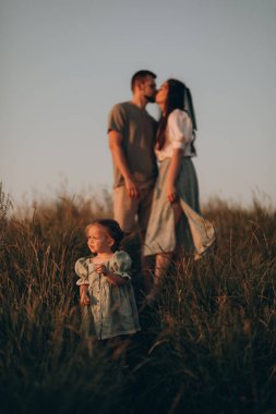 Mutlu aile gün batımında parkta yürür. Anne, baba ve bebek. Sağlıklı aile sahada oynar. Mutlu aile kavramı