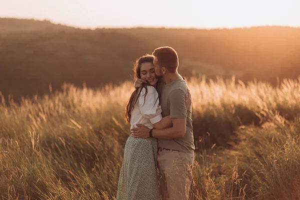 在夕阳西下的群山中 幸福的年轻夫妇紧紧地拥抱着 美丽地牵着手 — 图库照片