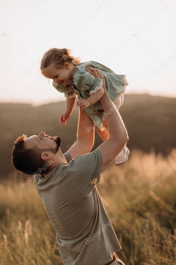 Father and child. Dad walking with baby daughter, outdoor sunset portrait. Family, happiness, parent-kid communication, care, fatherhood, everyday superhero concepts